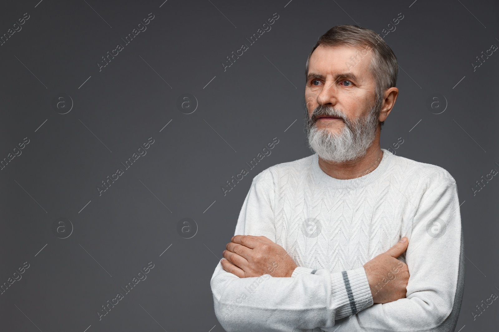 Photo of Portrait of mature man with crossed arms on grey background, space for text