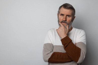 Photo of Portrait of mature man on light grey background, space for text