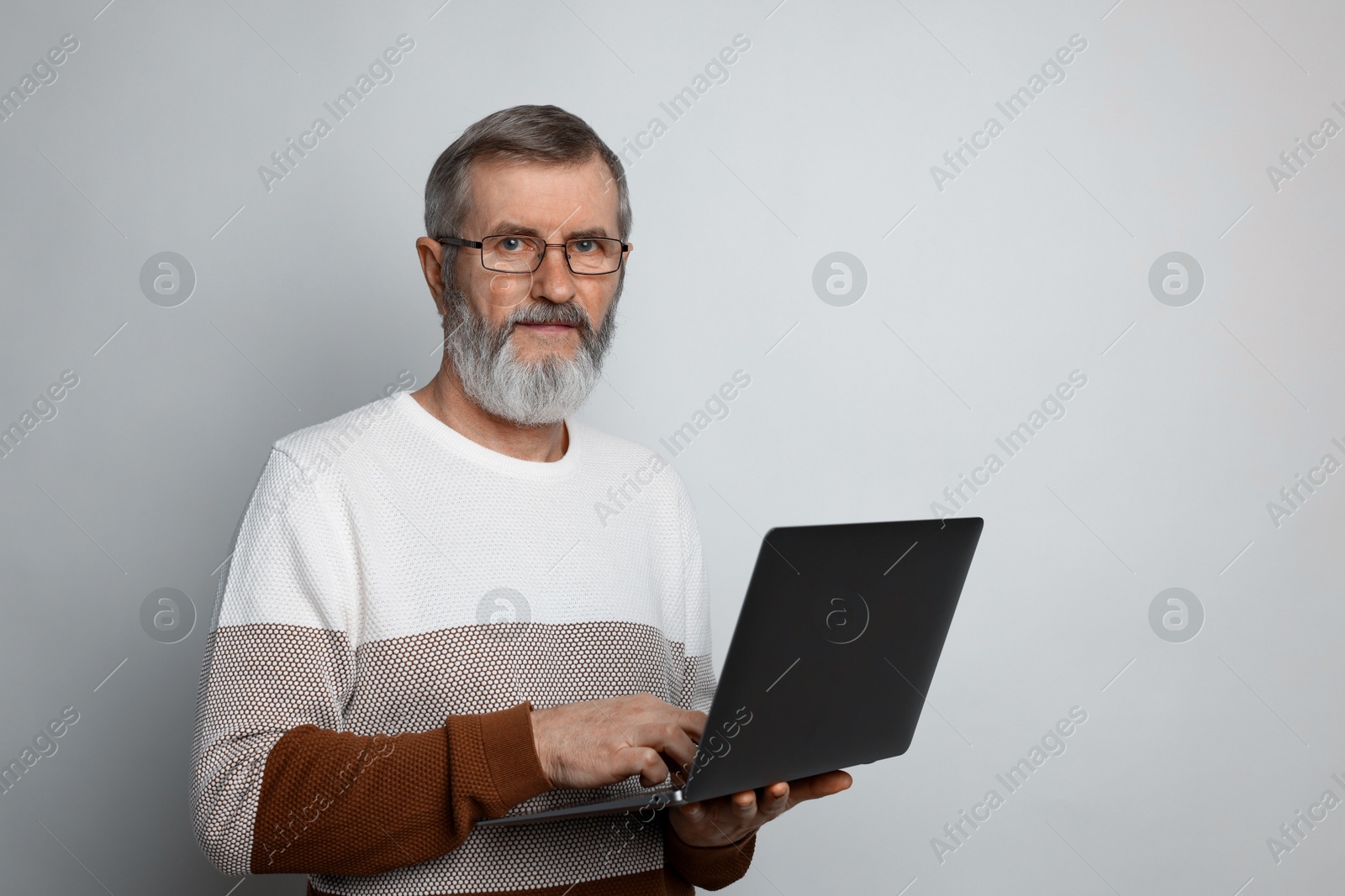 Photo of Mature man with laptop on light grey background