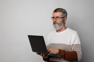 Photo of Mature man with laptop on light grey background