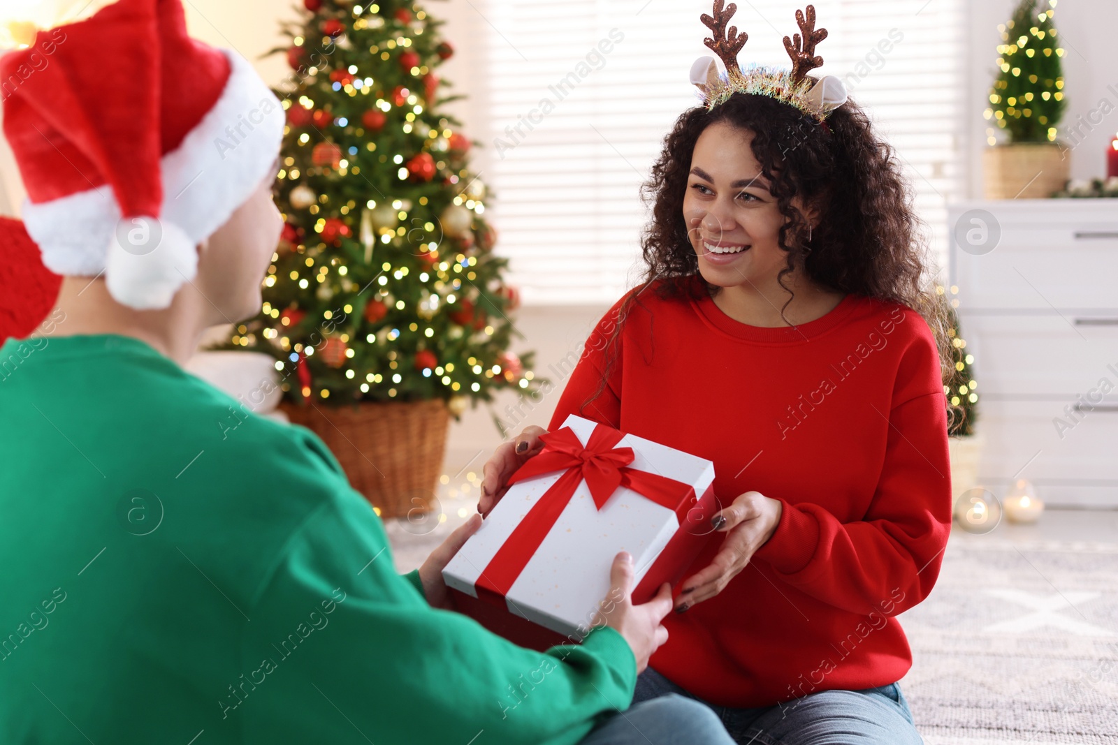 Photo of Young man giving Christmas gift to his happy girlfriend at home