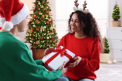 Photo of Young man giving Christmas gift to his happy girlfriend at home