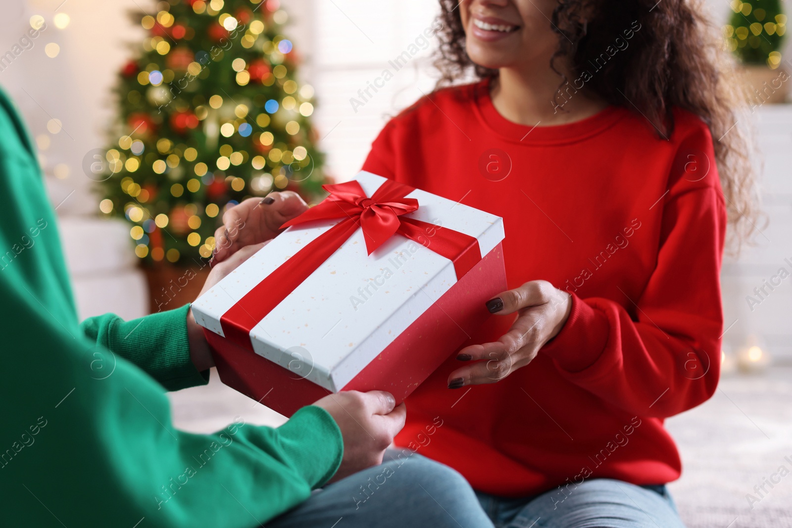 Photo of Young man giving Christmas gift to his happy girlfriend at home, closeup