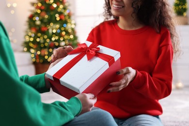 Photo of Young man giving Christmas gift to his happy girlfriend at home, closeup