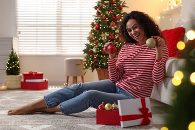 Photo of Happy young woman with Christmas gift at home