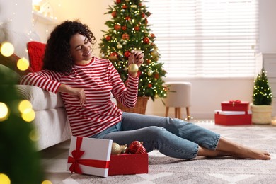 Photo of Happy young woman with Christmas gift at home