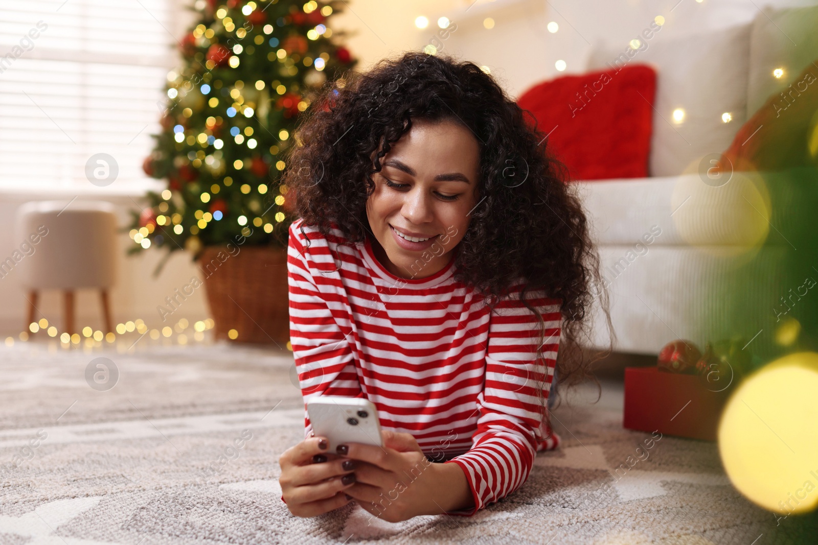 Photo of Happy young woman using smartphone at home. Christmas celebration