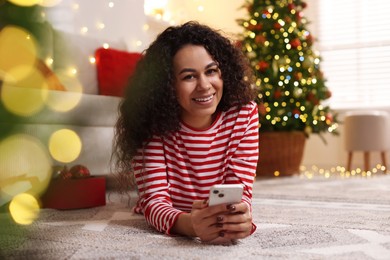 Photo of Happy young woman using smartphone at home. Christmas celebration