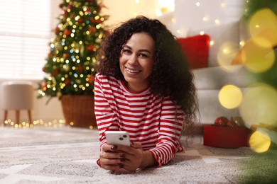 Photo of Happy young woman using smartphone at home. Christmas celebration