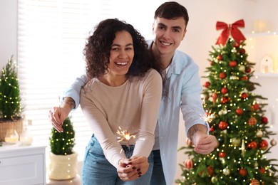 Photo of Happy couple with burning sparklers spending time together at home. Christmas celebration