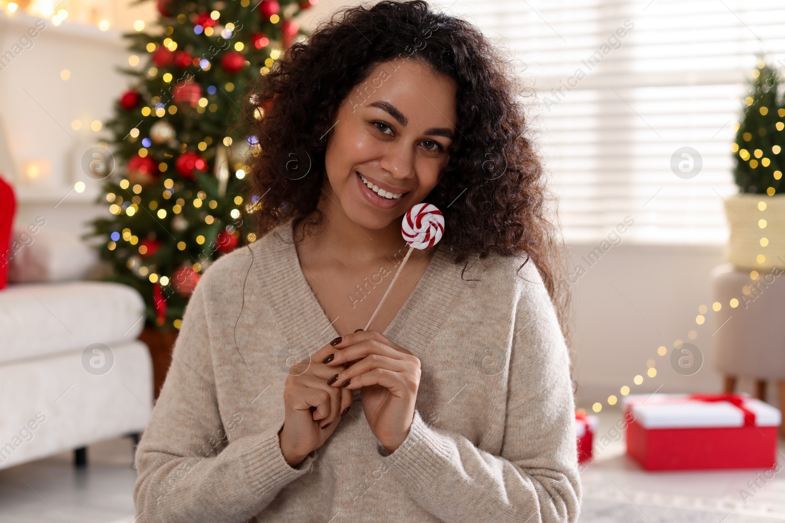 Photo of Happy young woman with lollipop at home. Christmas celebration