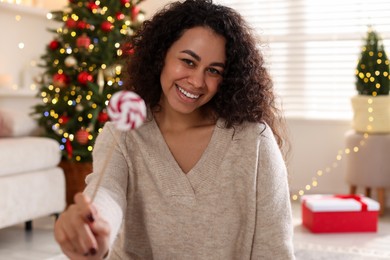 Photo of Happy young woman with lollipop at home. Christmas celebration