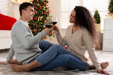 Photo of Happy couple with glasses of wine spending time together at home. Christmas celebration