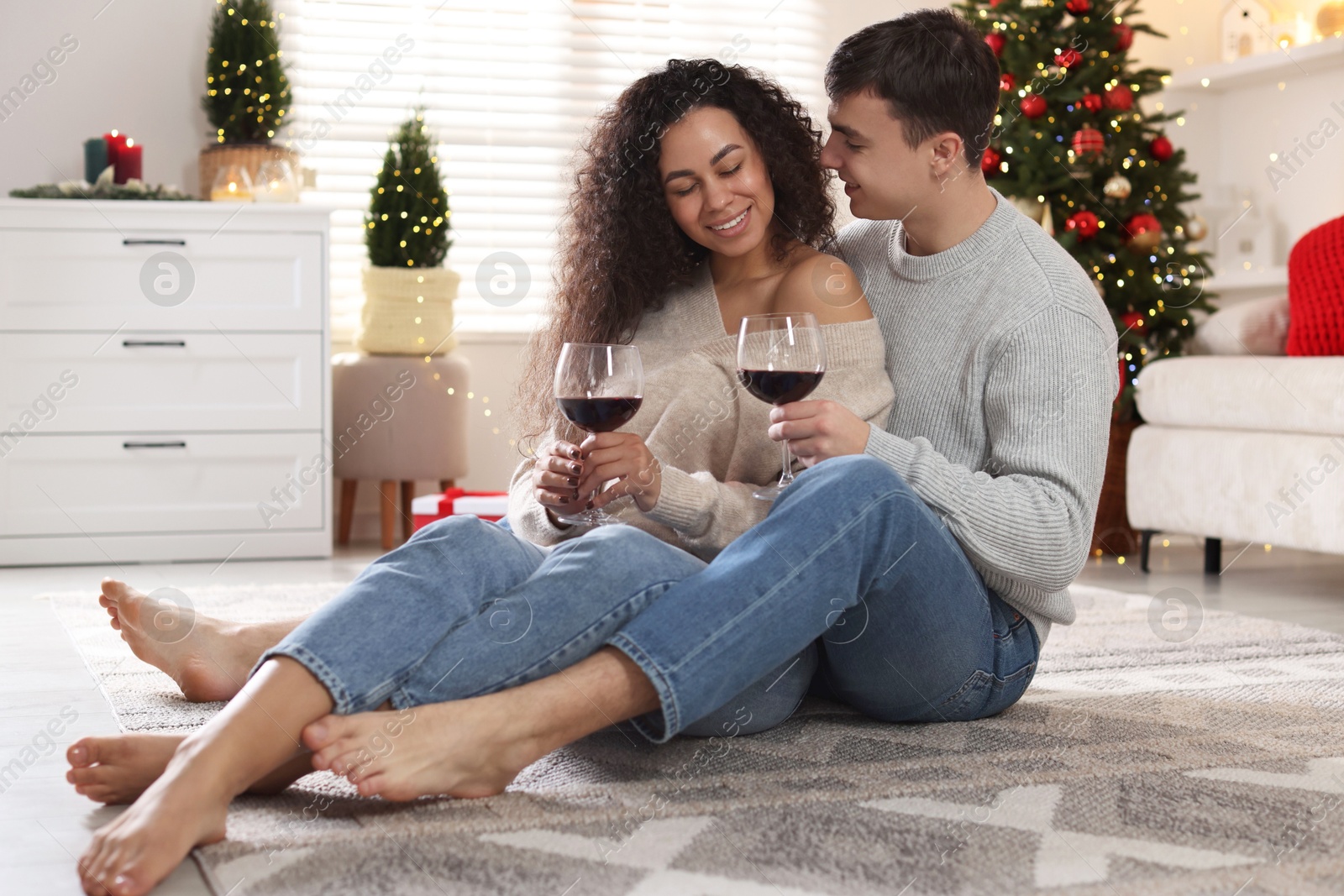 Photo of Happy couple with glasses of wine spending time together at home. Christmas celebration