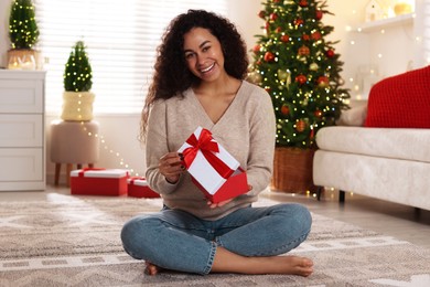 Photo of Happy young woman with Christmas gift at home