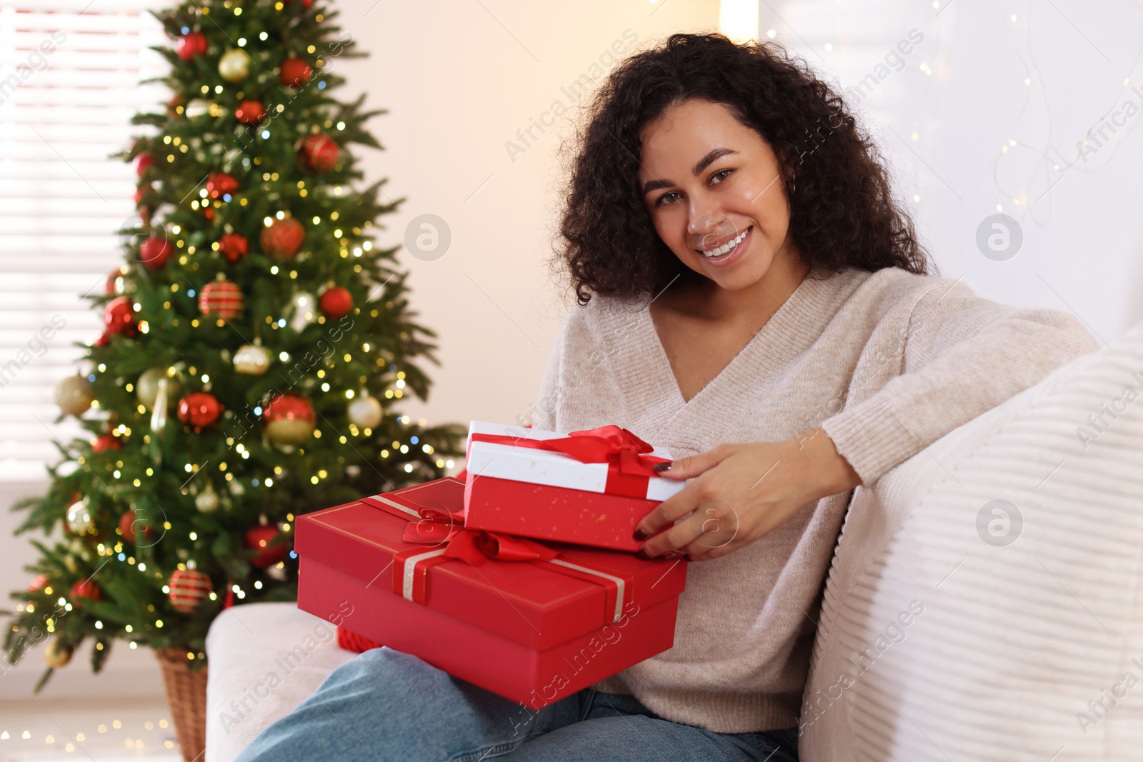 Photo of Happy young woman with Christmas gifts at home