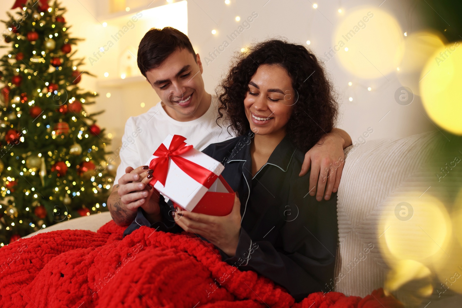 Photo of Happy couple with Christmas gift spending time together at home. Bokeh effect