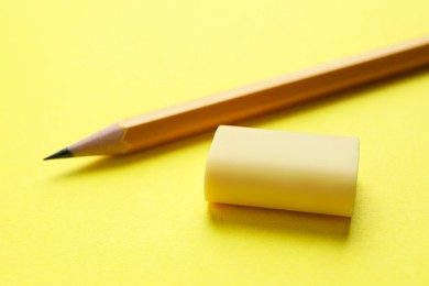 Photo of Eraser and pencil on yellow background, closeup