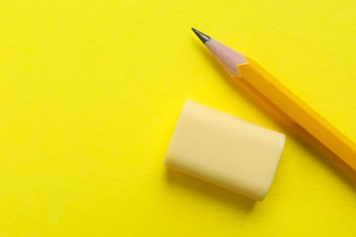 Photo of Eraser and pencil on yellow background, top view. Space for text