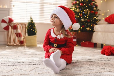 Photo of Little girl in Christmas costume with lollipop at home