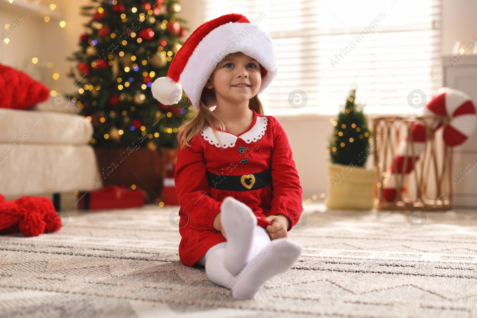 Photo of Little girl in Christmas costume with lollipop at home