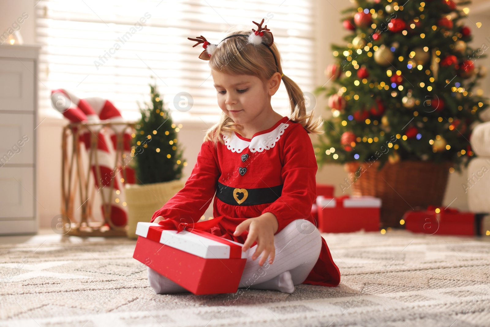 Photo of Little girl in Christmas costume with gift box at home