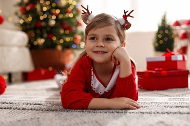 Photo of Little girl in Christmas costume lying on floor at home