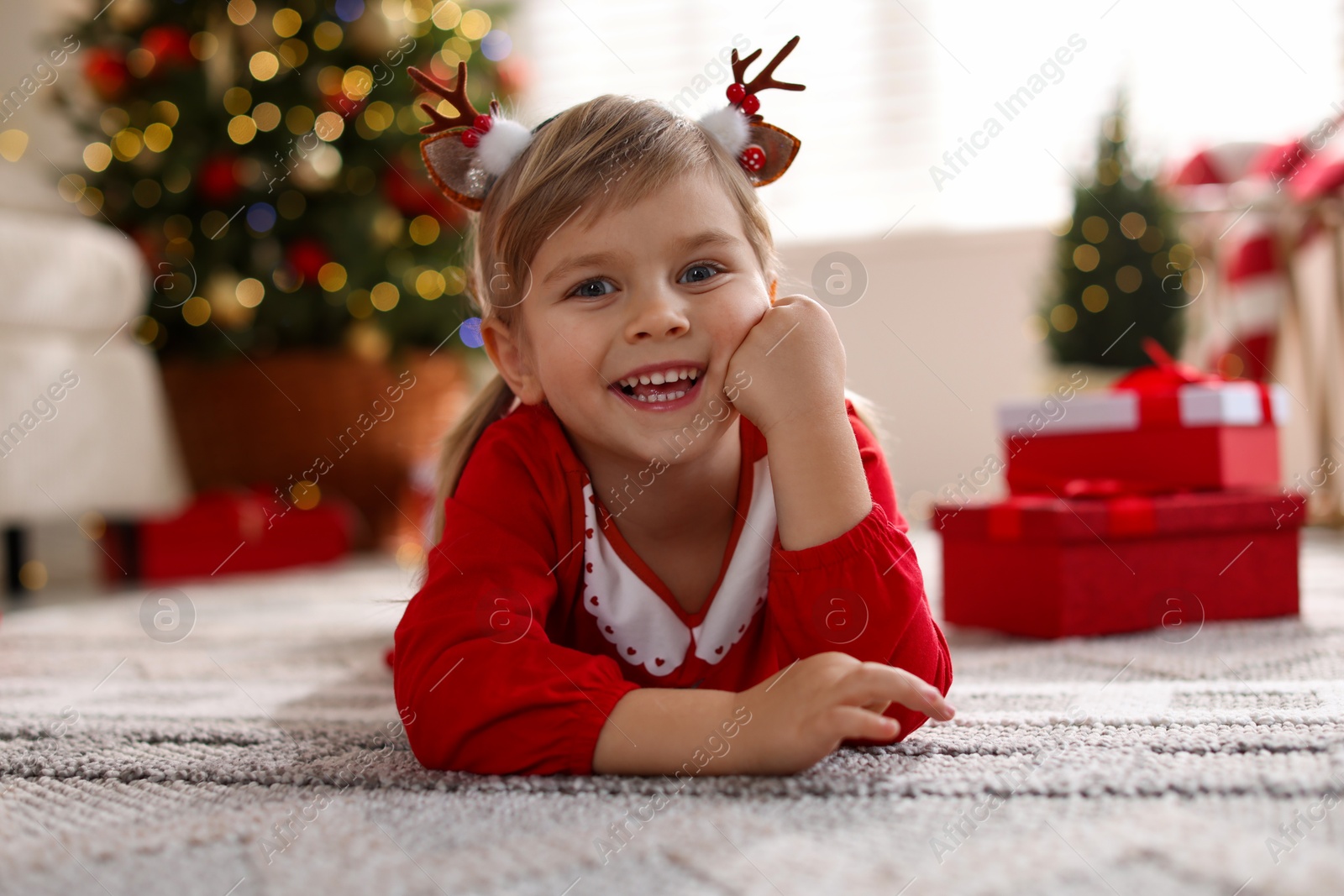 Photo of Little girl in Christmas costume lying on floor at home