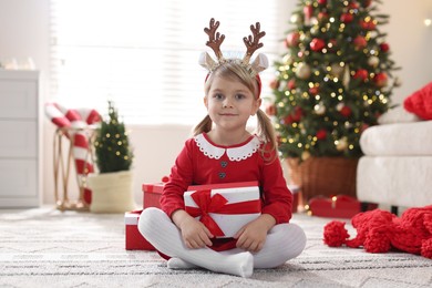 Photo of Little girl in Christmas costume with gift boxes at home