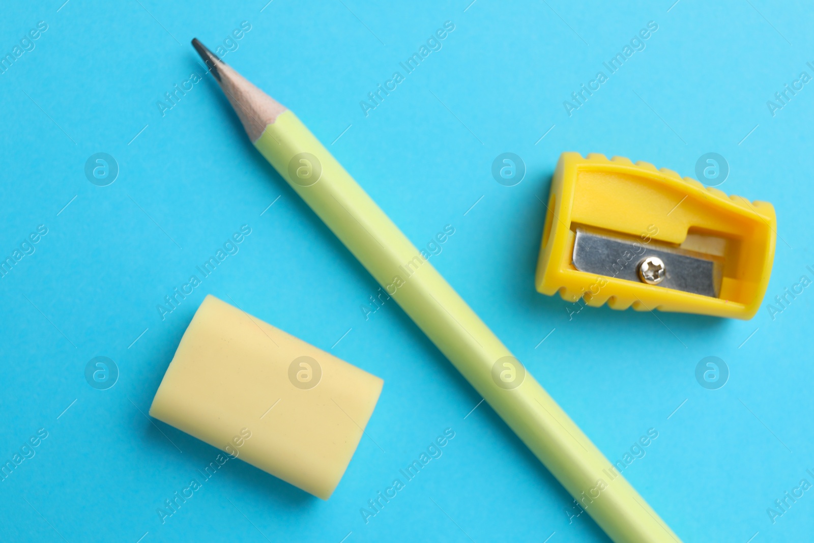 Photo of Eraser, pencil and sharpener on light blue background, top view