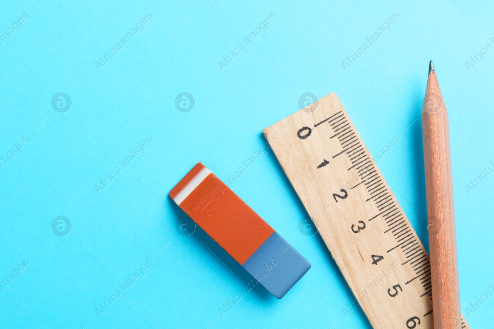 Photo of Eraser, pencil and ruler on light blue background, top view. Space for text