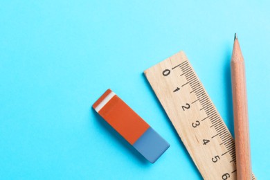 Photo of Eraser, pencil and ruler on light blue background, top view. Space for text