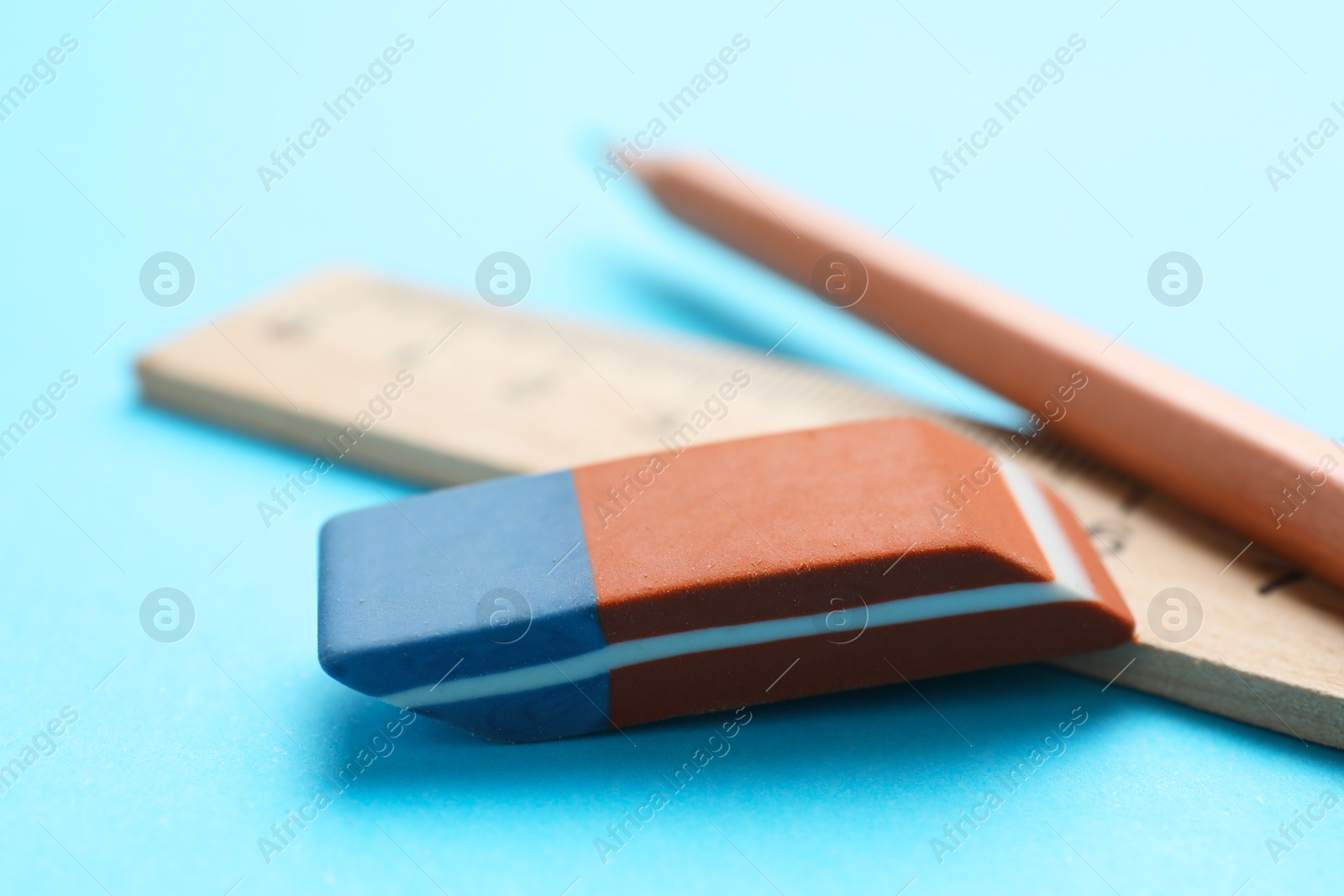 Photo of Eraser, pencil and ruler on light blue background, closeup