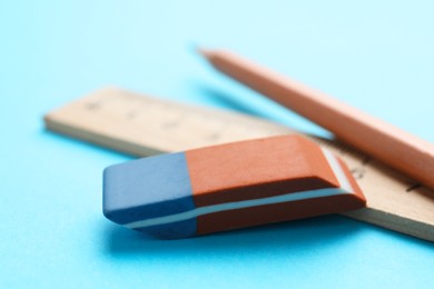 Photo of Eraser, pencil and ruler on light blue background, closeup