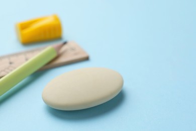 Photo of Eraser, pencil, ruler and sharpener on light blue background, selective focus. Space for text