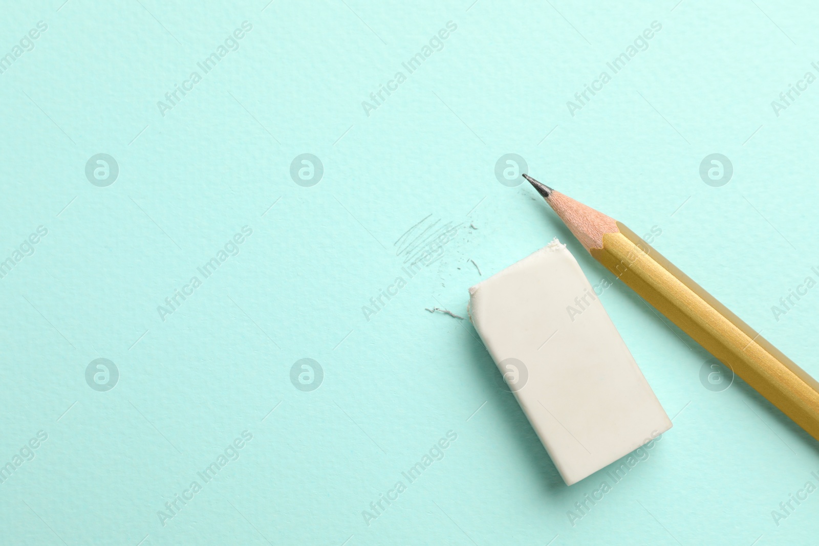 Photo of Eraser and pencil on light blue background, top view. Space for text