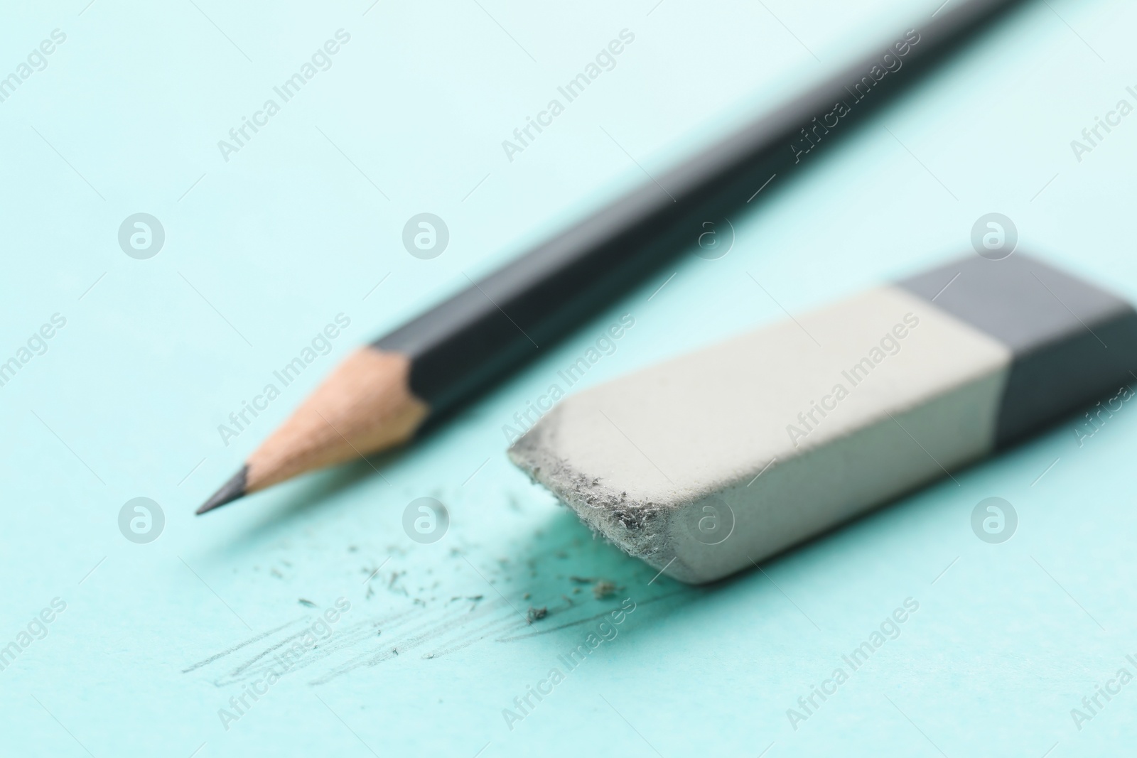 Photo of Eraser and pencil on light blue background, closeup