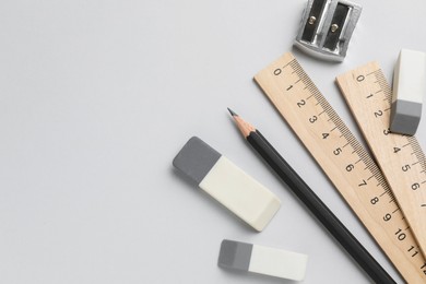 Photo of Erasers, pencil, sharpener and rulers on light background, top view. Space for text