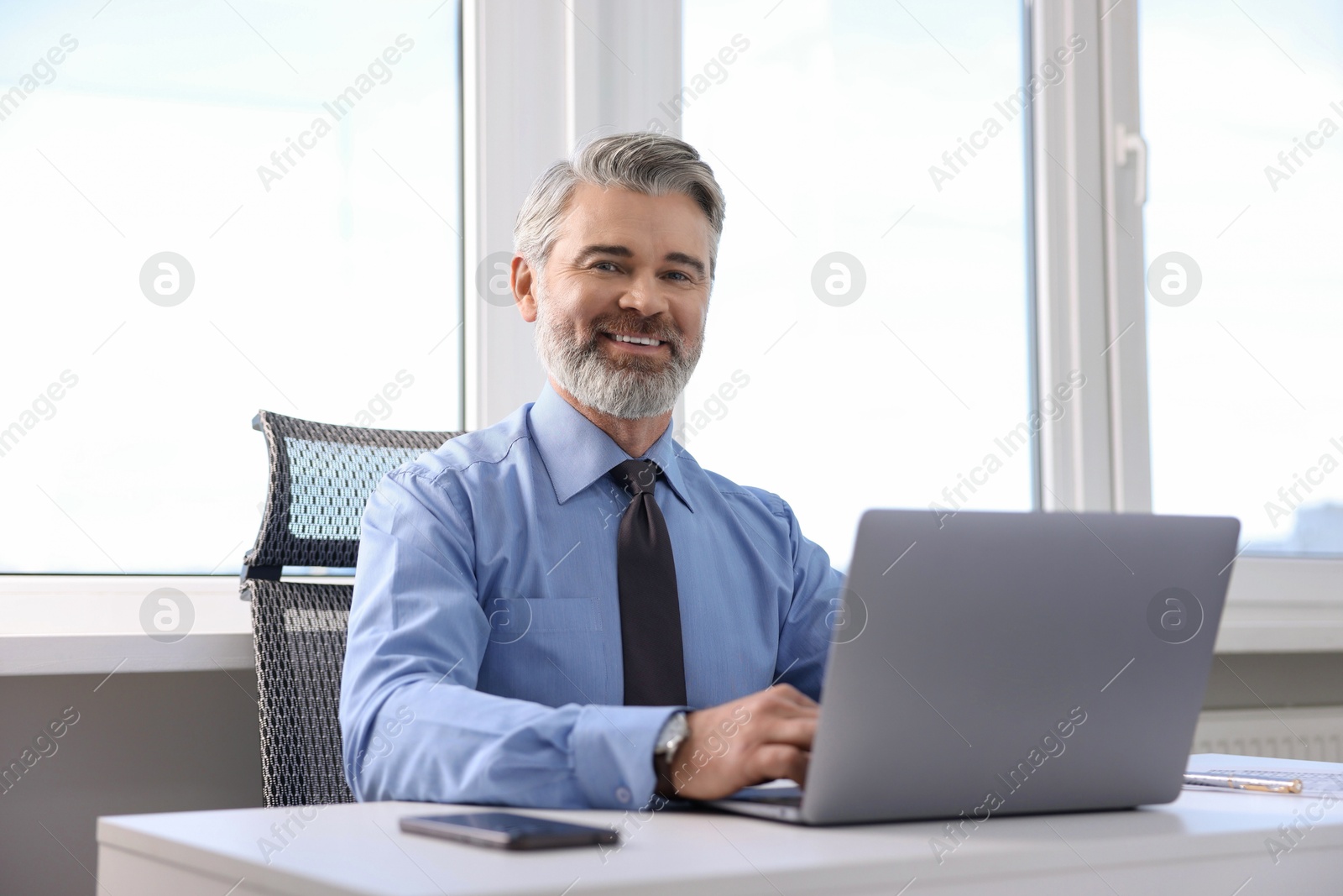 Photo of Banker working on laptop at desk in office