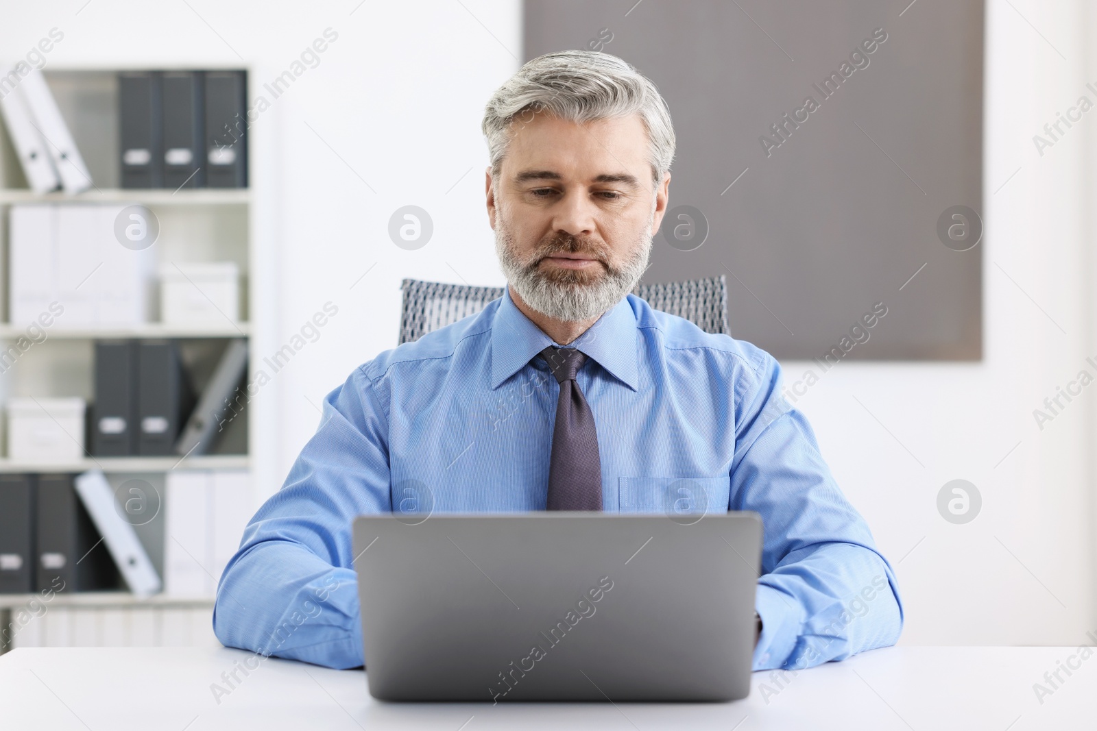 Photo of Banker working on laptop at desk in office