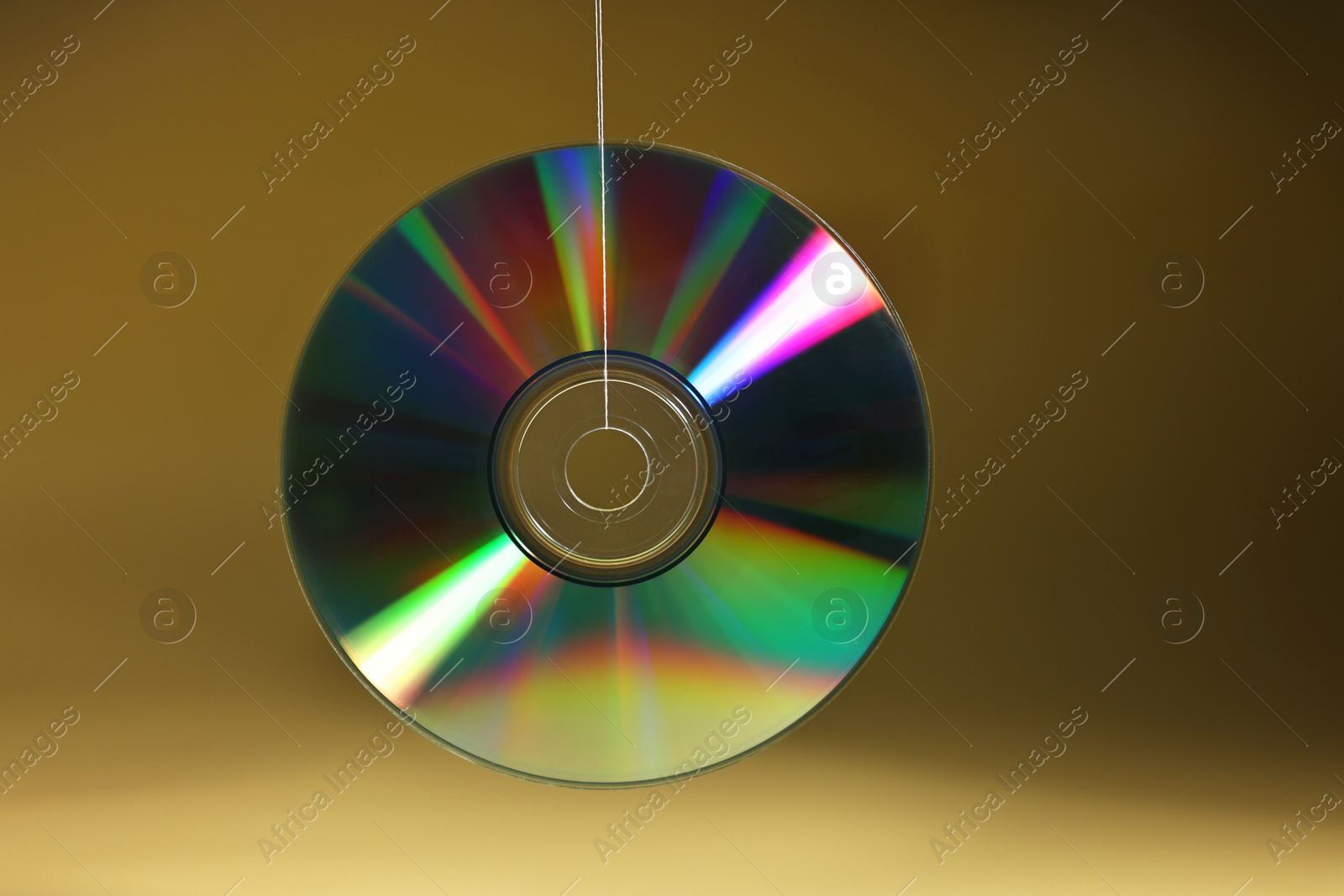 Photo of One shiny compact disc on dark yellow background