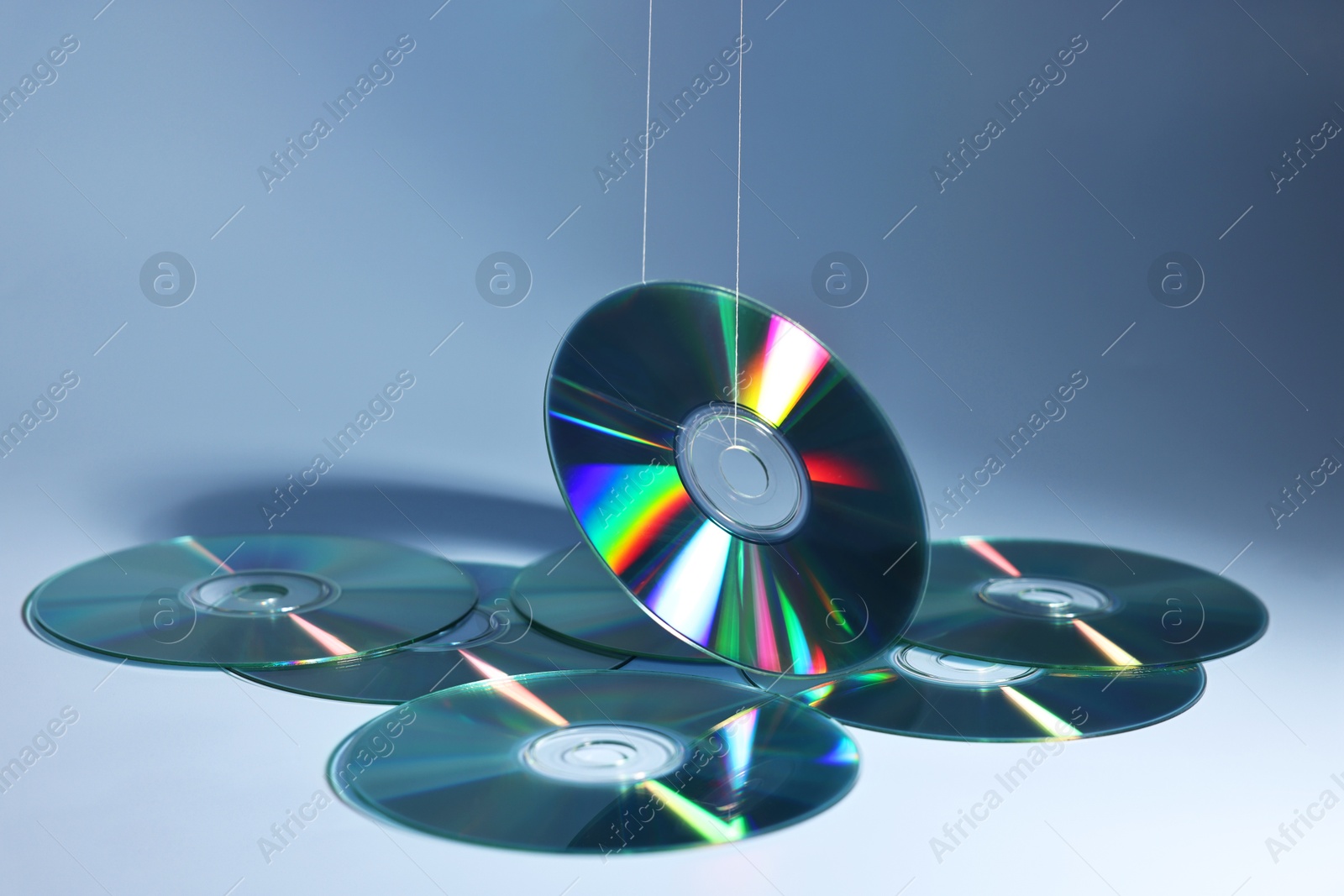 Photo of Many shiny compact discs on dusty blue background