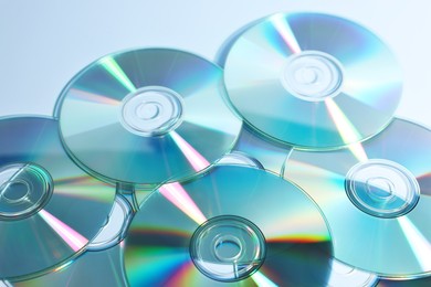 Photo of Many shiny compact discs on dusty blue background, closeup