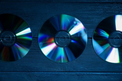 Photo of Shiny compact discs on wooden background, flat lay