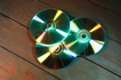 Photo of Shiny compact discs on wooden background, above view