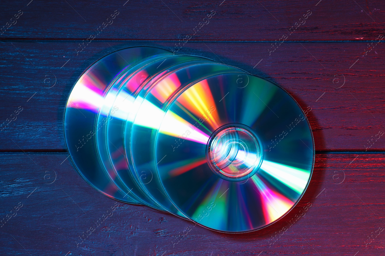 Photo of Shiny compact discs on wooden background, top view