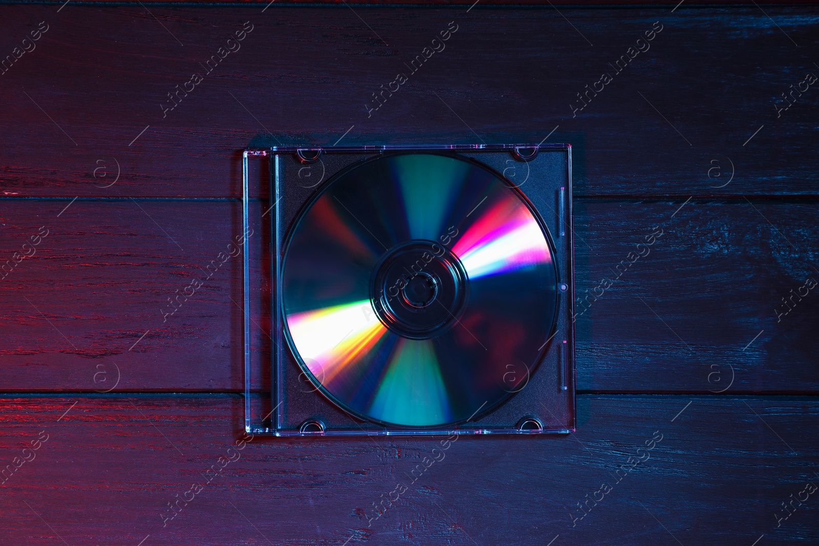 Photo of One compact disc in jewel case on wooden background, top view