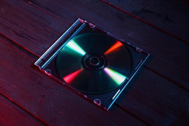 Photo of One compact disc in jewel case on wooden background, closeup