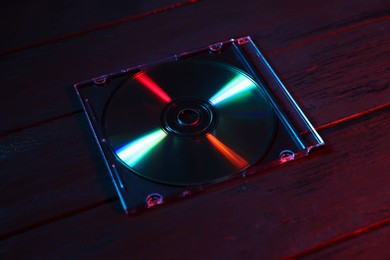 Photo of One compact disc in jewel case on wooden background, closeup