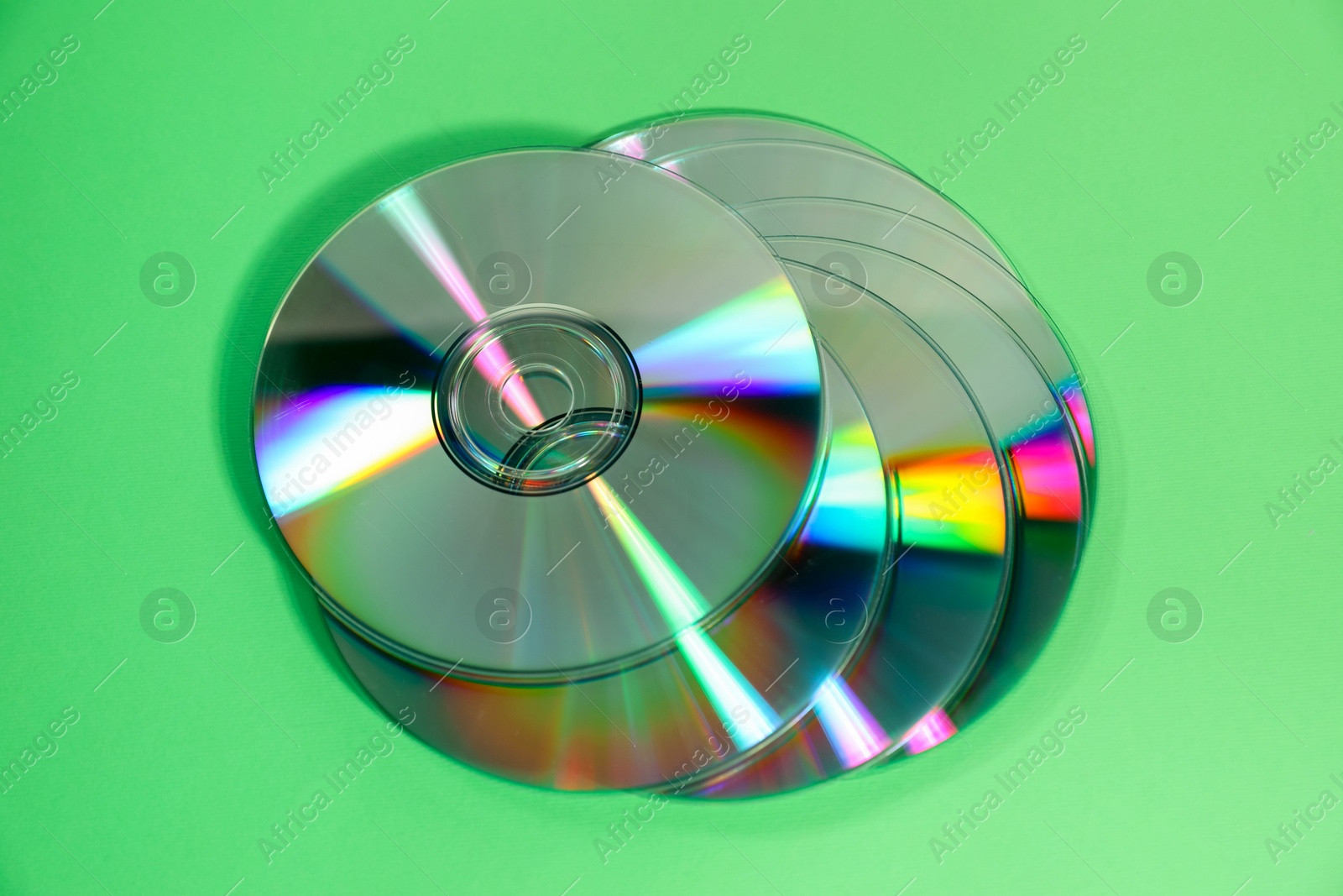 Photo of Many compact discs on green background, top view